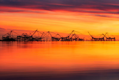 Silhouette cranes against sky during sunset