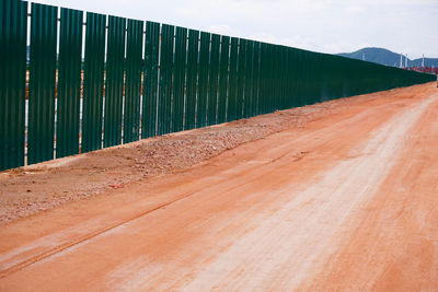 Road leading towards wall against sky