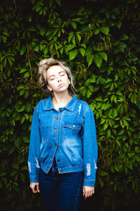 Young woman standing against plants