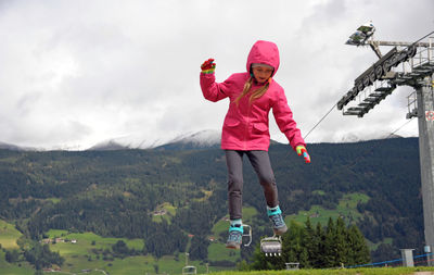 Full length of happy girl on mountain against sky