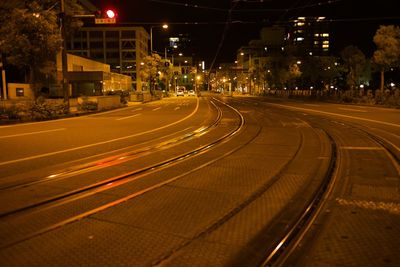 Light trails on street amidst illuminated buildings in city at night