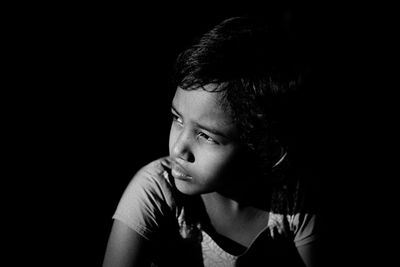 Close-up of young woman against black background