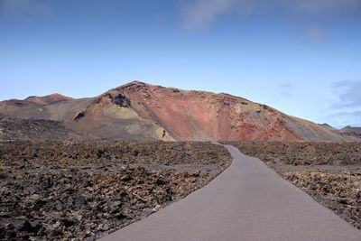 Road by mountain against sky