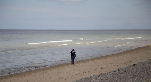 Full length of man standing on beach against sky