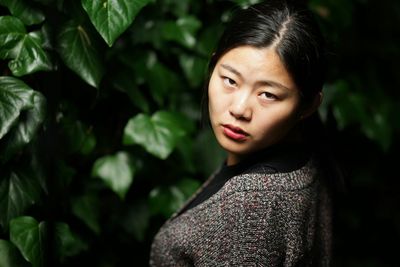 Close-up portrait of young woman against plants