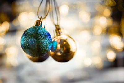 Close-up of baubles handing against christmas decoration