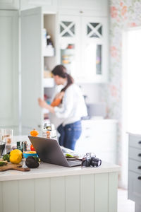 Working mother with daughter preparing for blog in kitchen at home