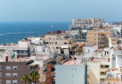 High angle view of townscape by sea against clear sky