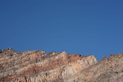 Low angle view of rocks against clear blue sky