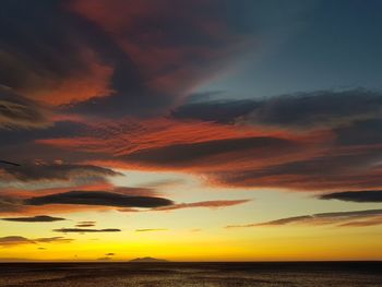 Scenic view of sea against dramatic sky during sunset