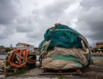 Stack of fishing net at harbor against sky