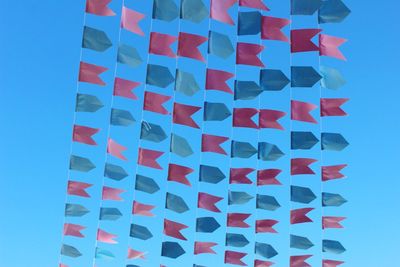 Low angle view of multi colored umbrellas against blue sky