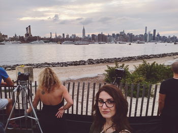 Friends on river by city against sky