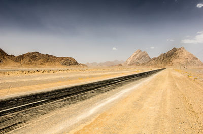 Road leading towards desert against sky