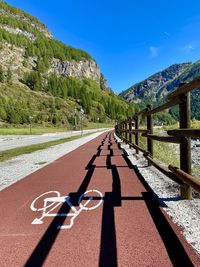 Road by mountain against sky on sunny day