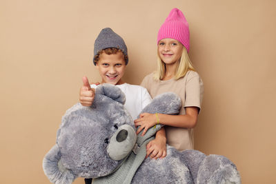 Portrait of cute girl with stuffed toy against beige background