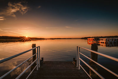 Pier over sea against sky during sunset