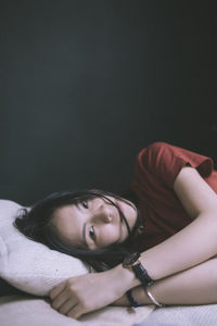 Portrait of young woman lying on bed at home