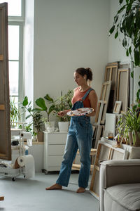 Side view of young woman using mobile phone while sitting on sofa at home