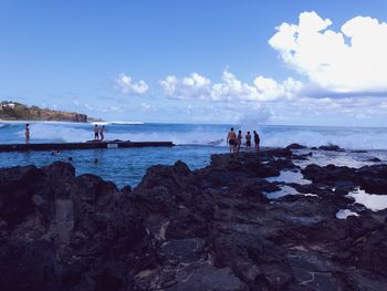 People at beach against blue sky