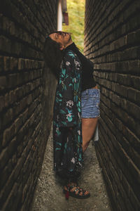 Side view of young woman standing against wall