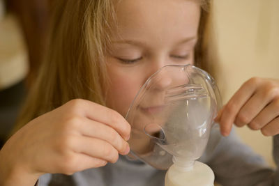 A sick child makes inhalation with a nebulizer at home, he holds a mask from which steam