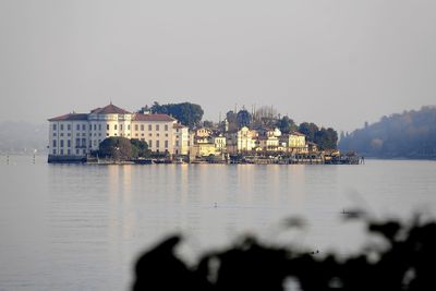 Buildings by sea against clear sky