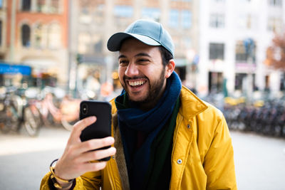 Happy young man using mobile phone in city