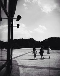 People walking on road against cloudy sky