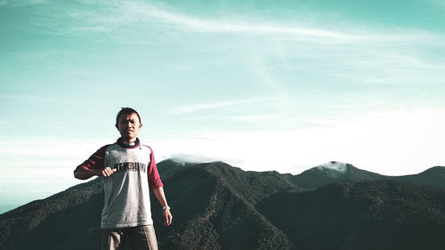 Portrait of smiling man standing on mountain against sky