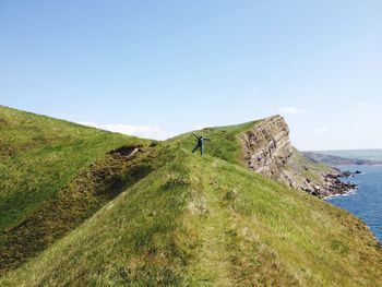 Mid distance view of person standing on cliff by sea against sky at tyneham village