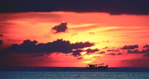 Silhouette boat in sea against orange sky