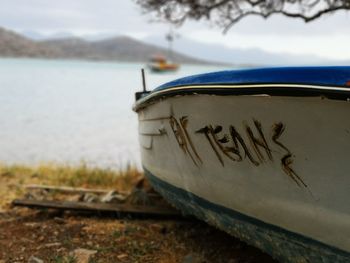 Close-up of boat moored on beach against sky