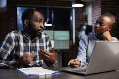 Male and female colleague using laptop at table