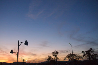 Low angle view of street lights against sky at sunset