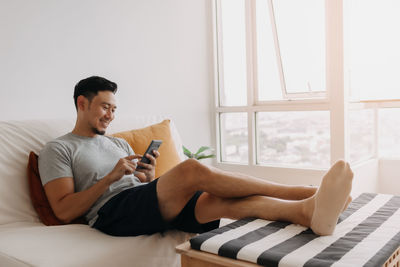 Young woman using mobile phone while sitting on sofa at home
