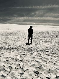 Alone on the dune - rear view of silhouette man standing on beach against sky