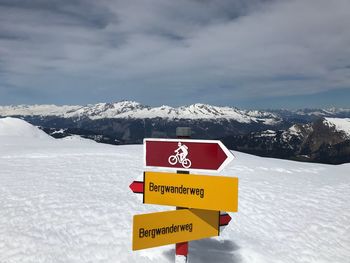 Warning sign on snowcapped mountain against sky