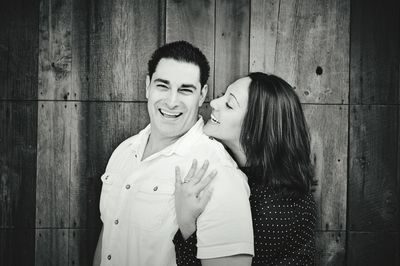 Happy young couple embracing against wooden wall