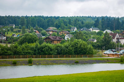 Houses by river and buildings against sky