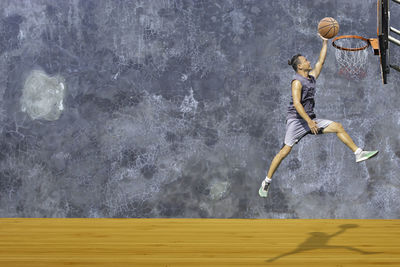 Side view of man jumping against blurred background
