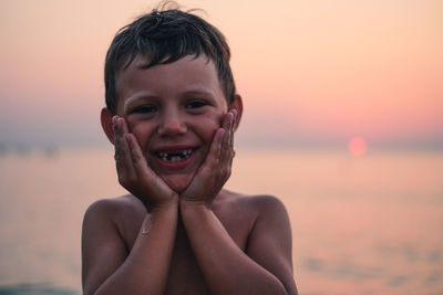 Portrait of smiling boy against sea during sunset