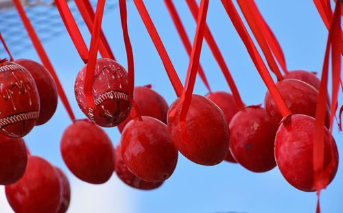 Close-up of easter eggs hanging from ribbons against sky