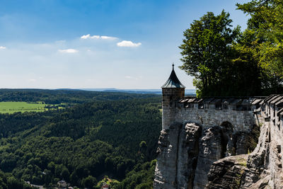 Trees by historic building against sky