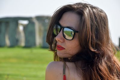 Rear view of young woman wearing sunglasses against stonehenge
