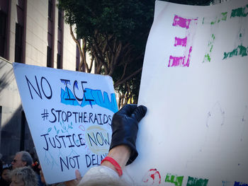 Low section of man holding text on sign in city