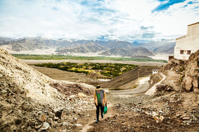 Rear view of man standing on mountain against sky
