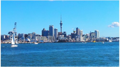 City at waterfront against blue sky