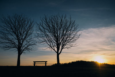 Silhouette bare tree on field against sky at sunset