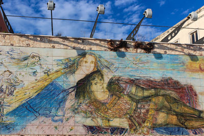 Low angle view of graffiti on old bridge against sky